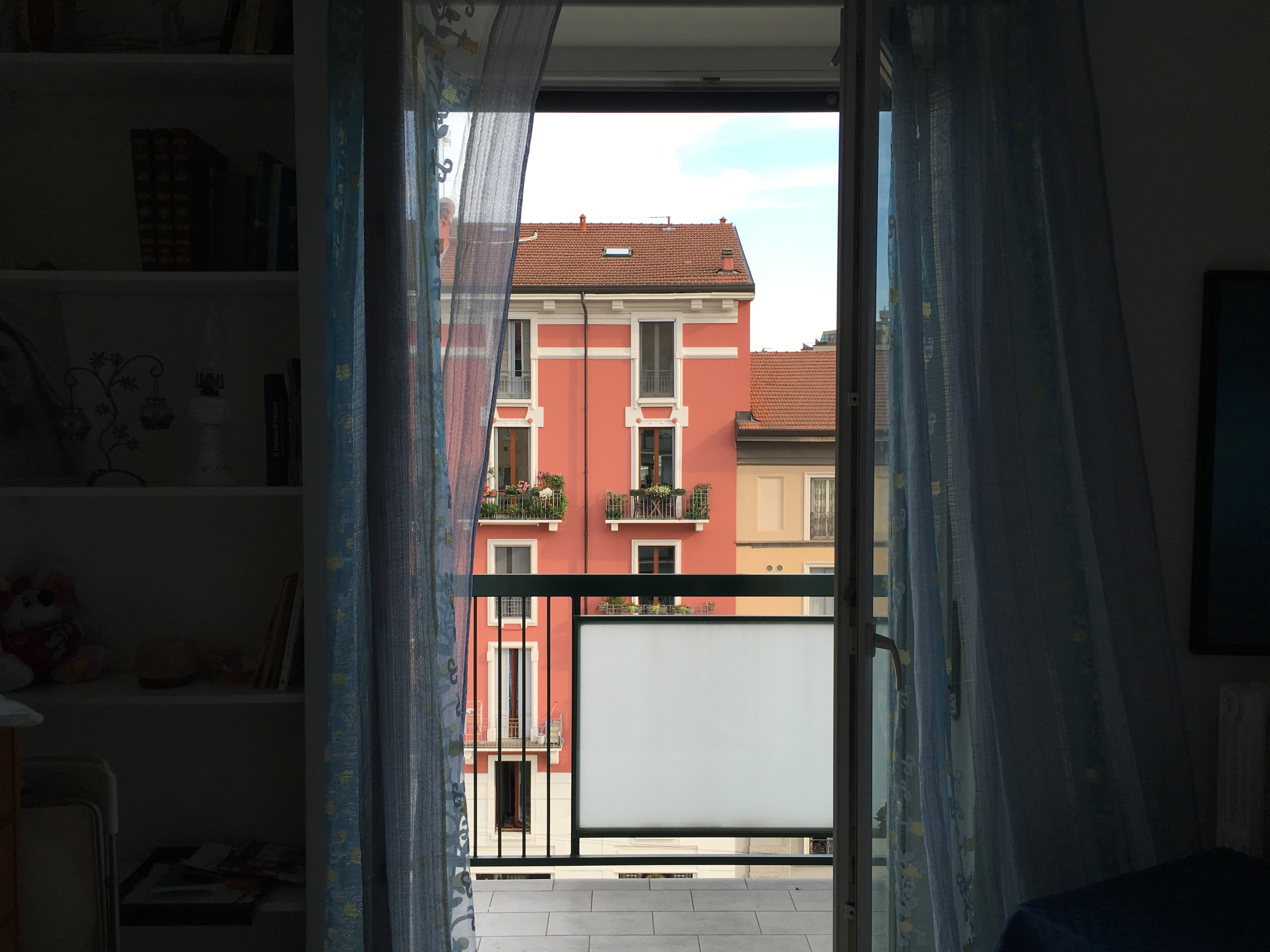 A red apartment building framed by an open balcony door