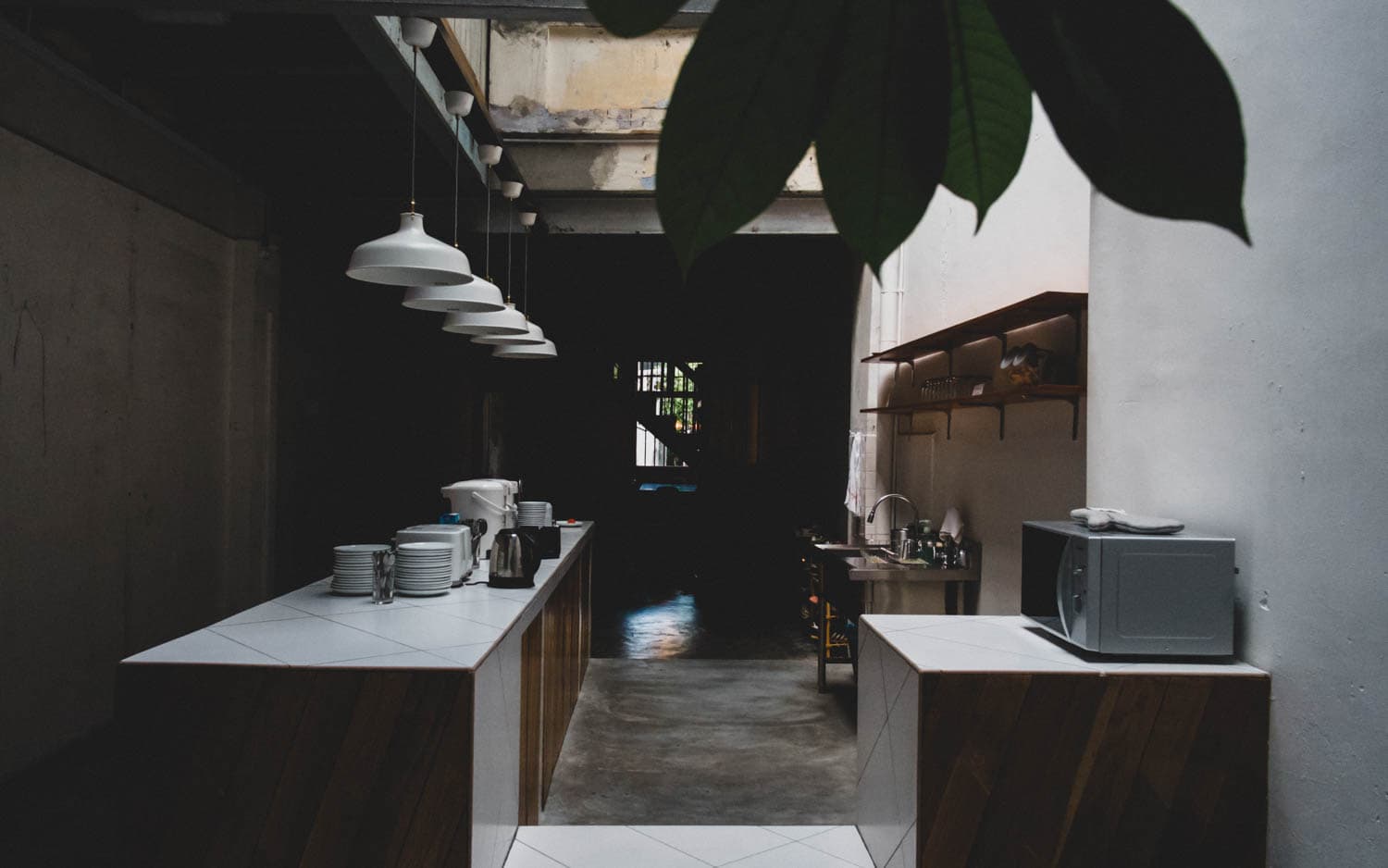 A quiet open kitchen lit by hanging lamps