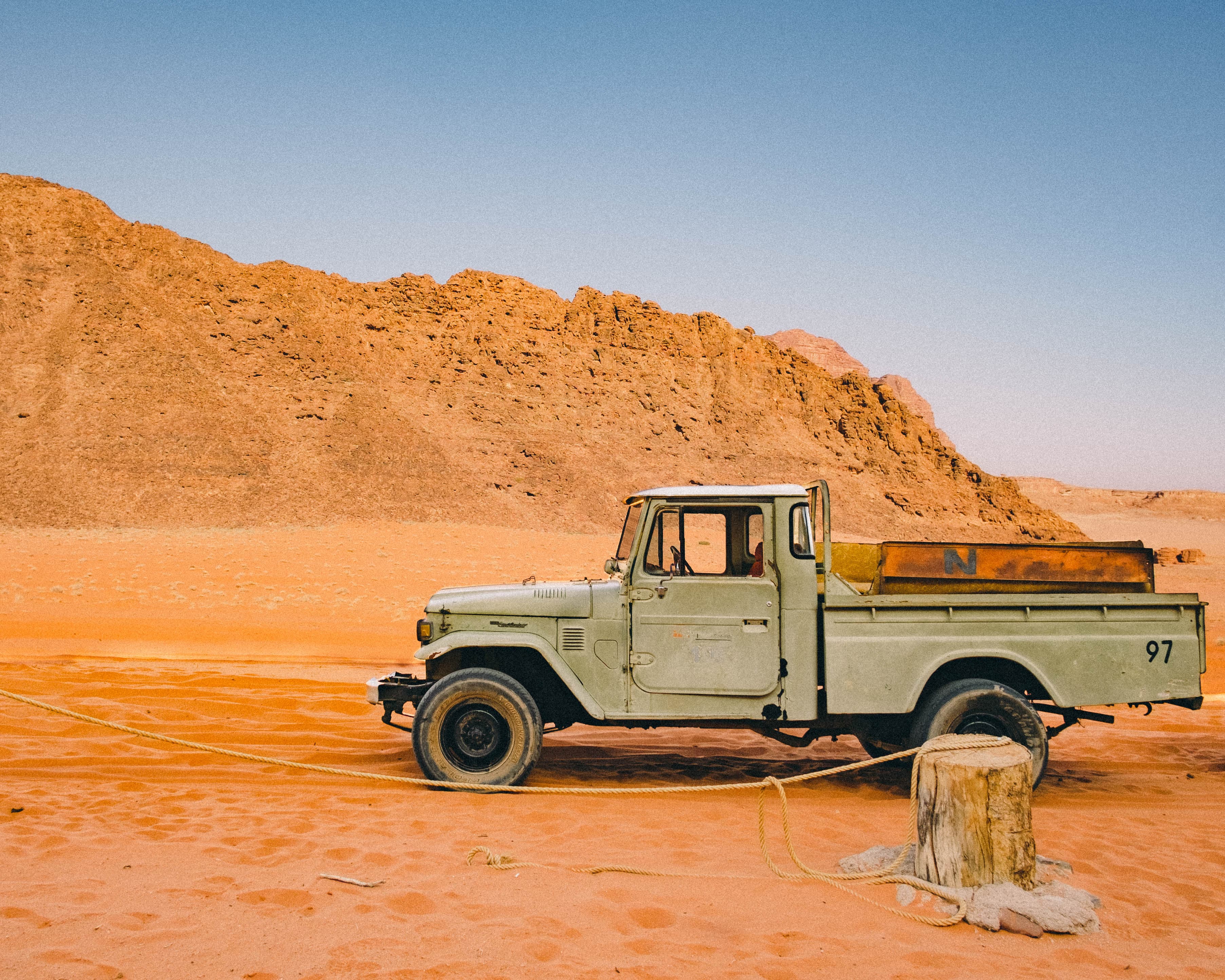 A pickup truck parked on orange desert sand