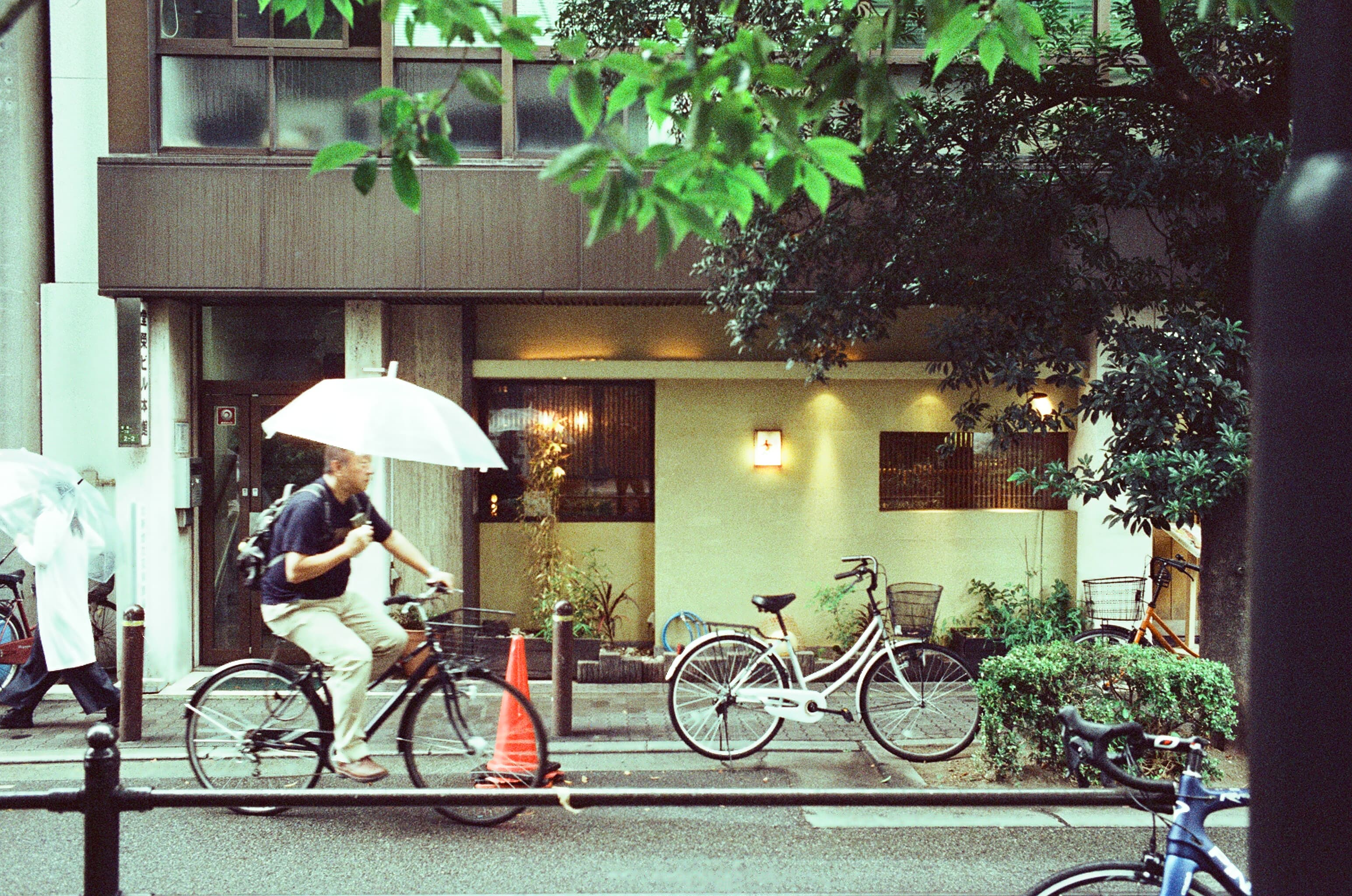 A cyclist carrying an umbrella on a rainy street