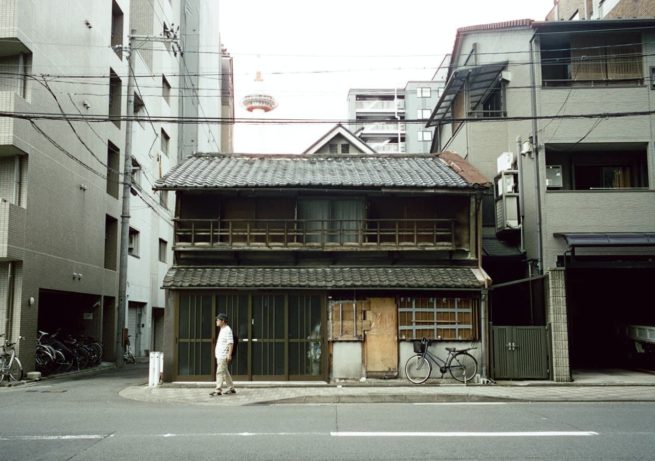 A traditional wooden house between modern city buildings
