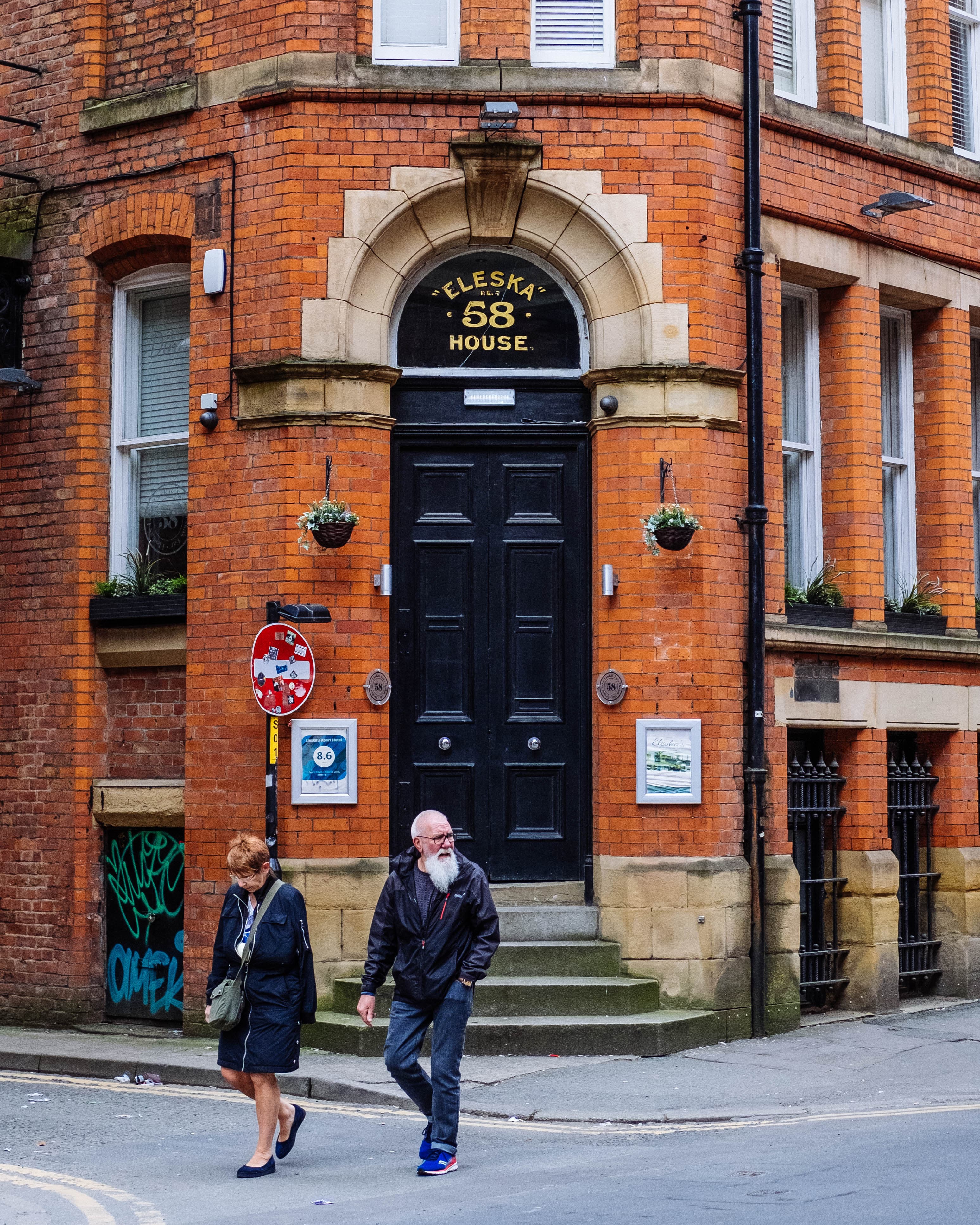 Pedestrians passing a red-brick pub on a street corner