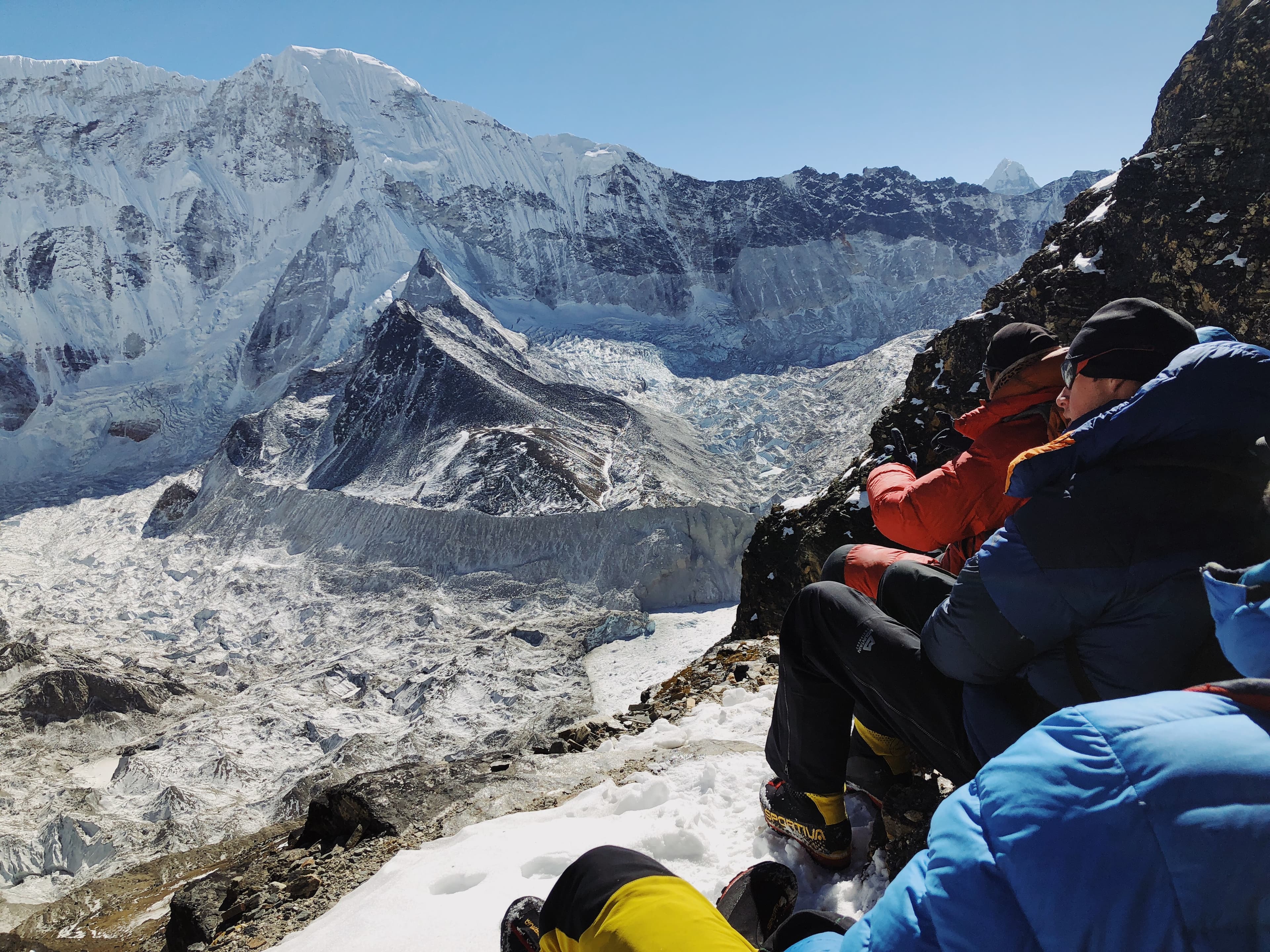 Trekkers resting above a glacier in the Himalayas