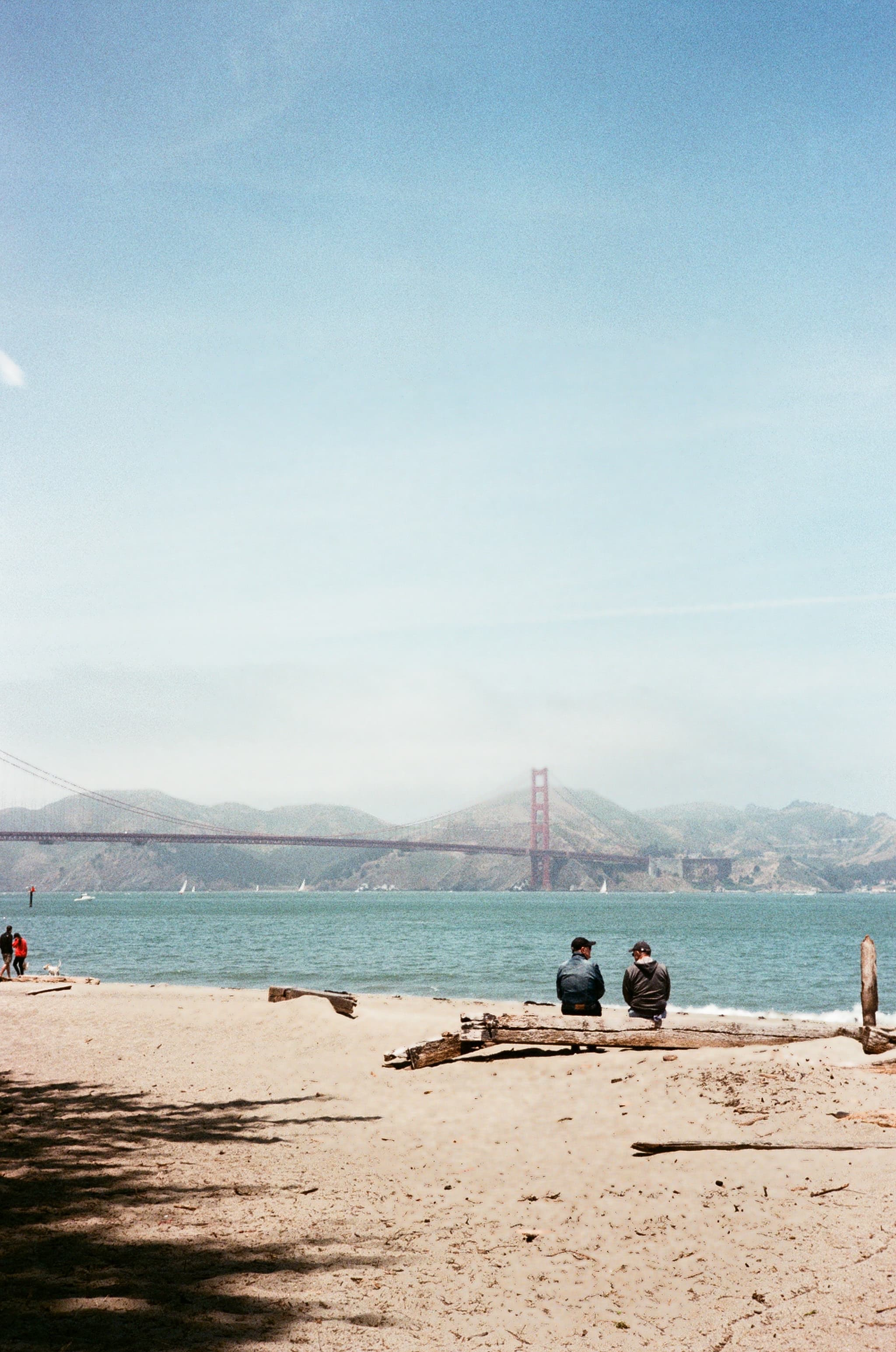 People on a beach with the Golden Gate Bridge in the distance