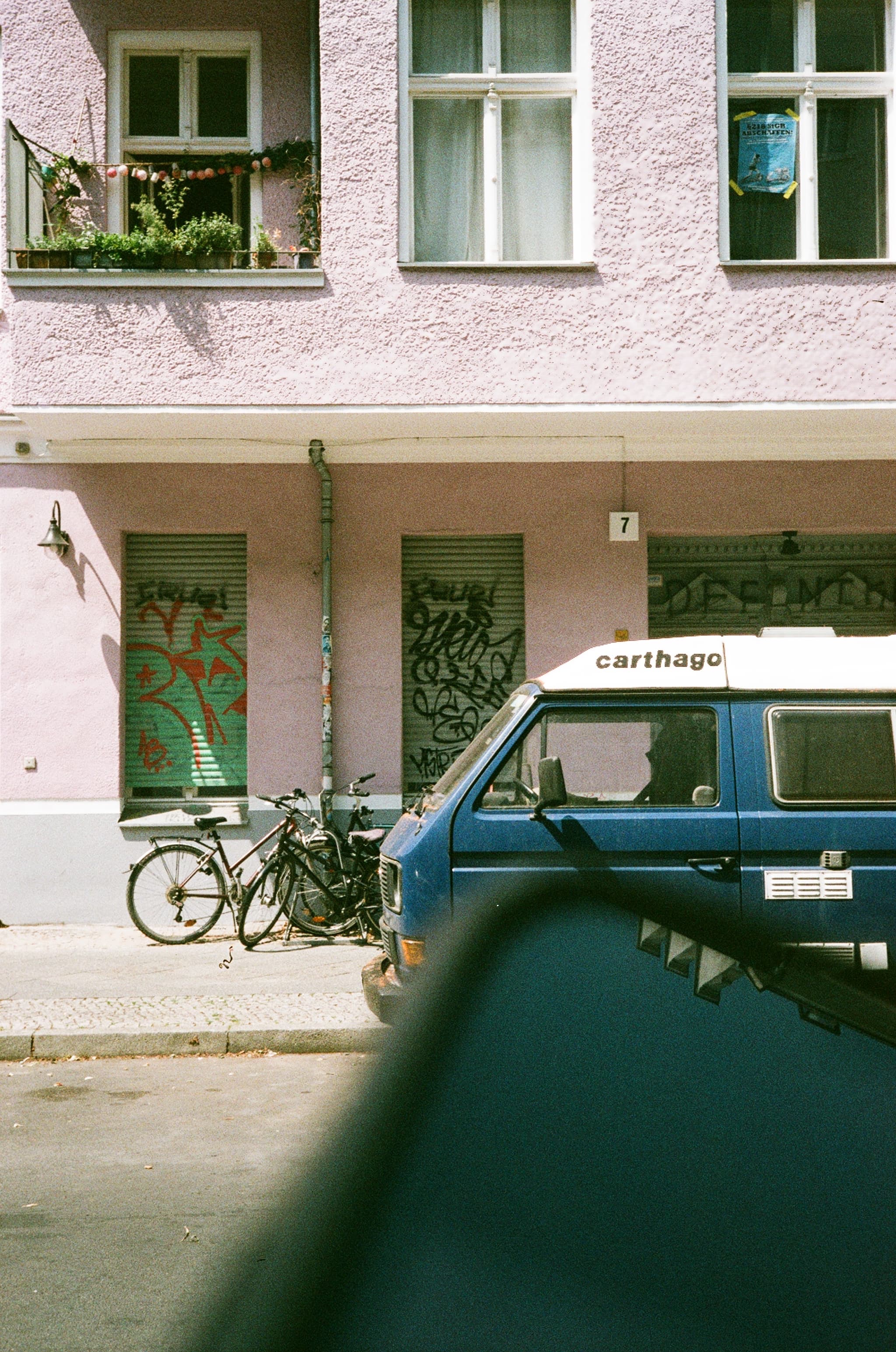A parked car and bicycles outside an apartment building