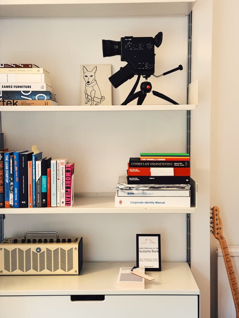 Books, a camera and small objects arranged on a shelf