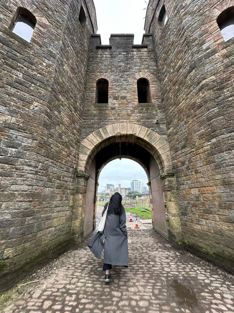 A person walking through a medieval stone arch