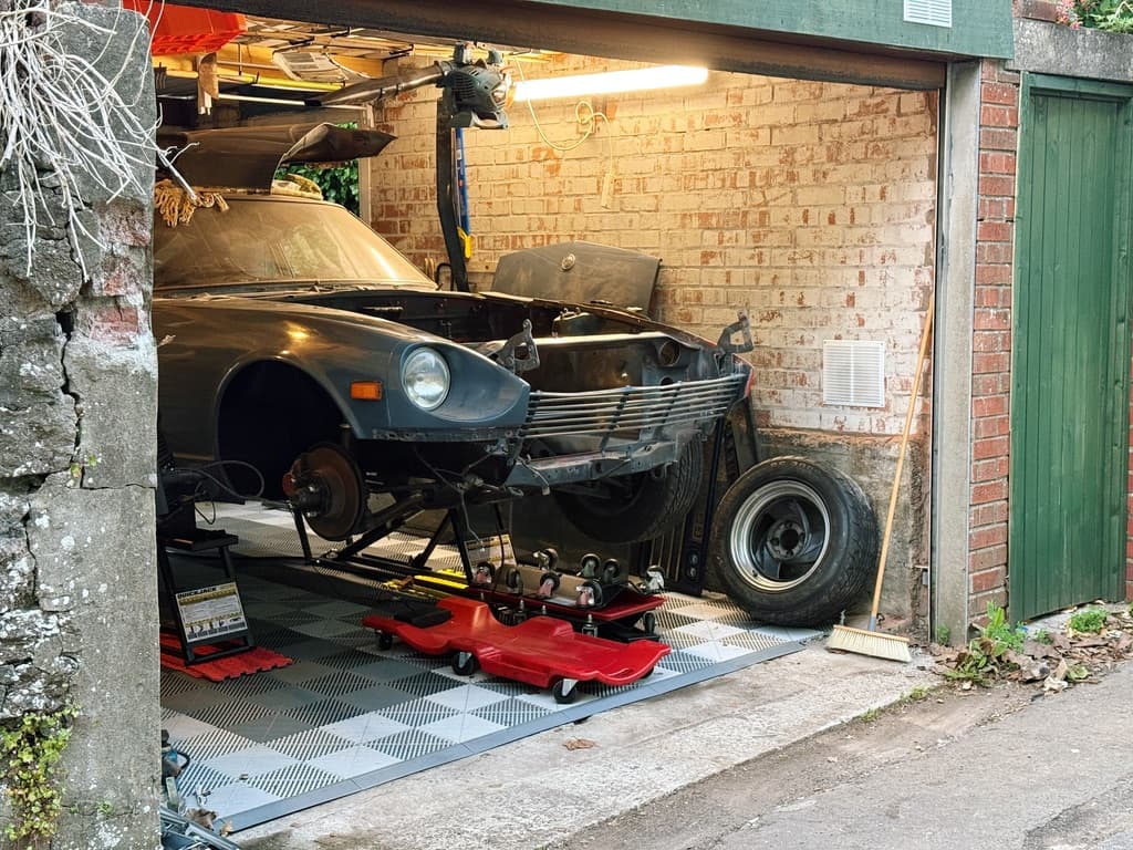 A classic car raised inside a brick garage